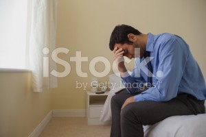 stock-photo-43936880-mournful-man-sitting-head-in-hands-on-his-bed