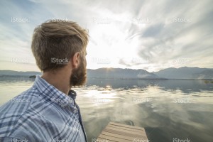 stock-photo-82674335-young-man-relaxes-on-lake-pier-looks-at-view