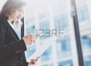 54418828-femme-pbusiness-portant-le-costume-regardant-smartphone-et-la-tenue-des-documents-dans-les-mains-esp