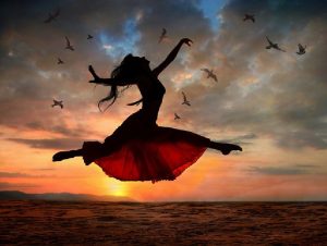 Dramatic image of a woman jumping above the ocean at sunset, silhouette