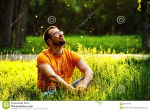 un-homme-rflchi-heureux-de-rveur-s-assied-sur-l-herbe-verte-en-parc-65618135